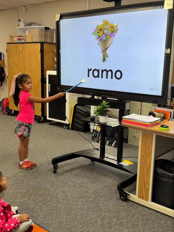 A student points to a word on a television that says, "Ramo."."