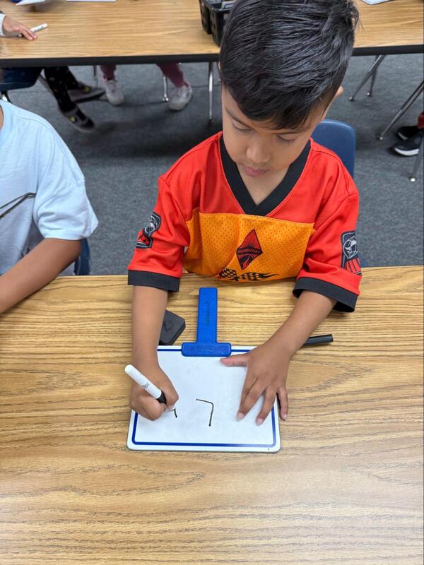 A student writes the letter "L."