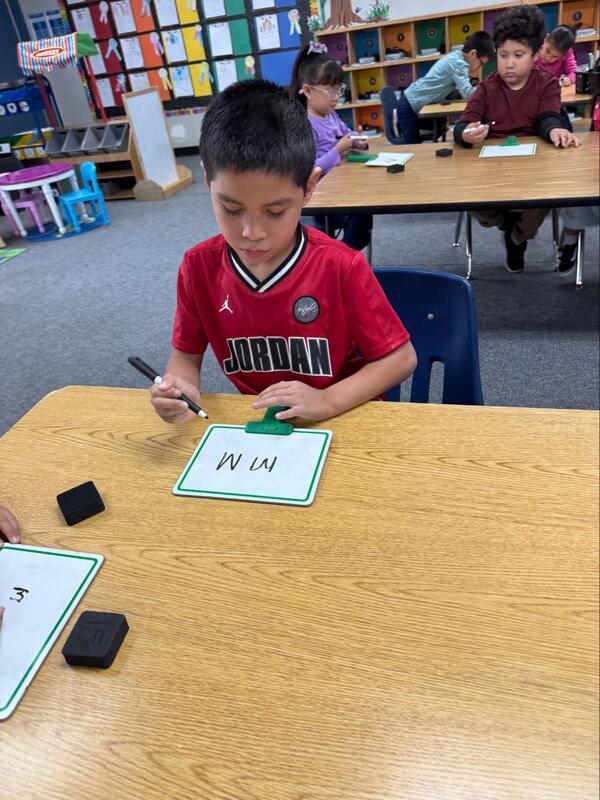 A student writes the letter "M."