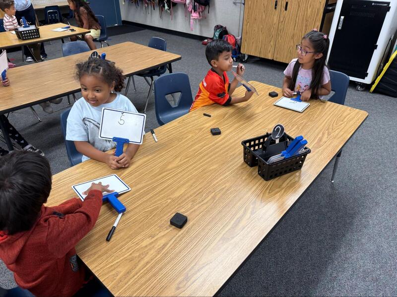 Students practice writing the letter "Ss" and sharing with classmates.