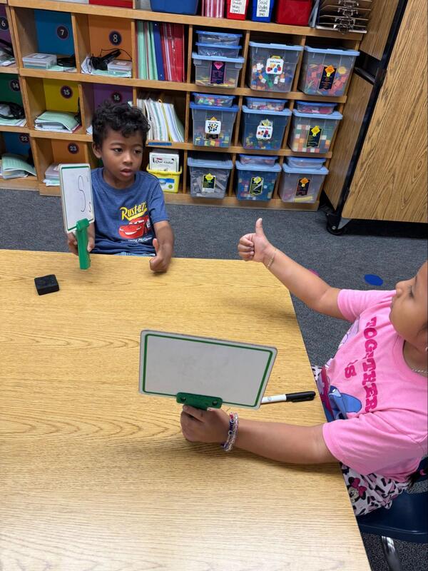 Students practice writing the letter "Ss" and sharing with classmates.