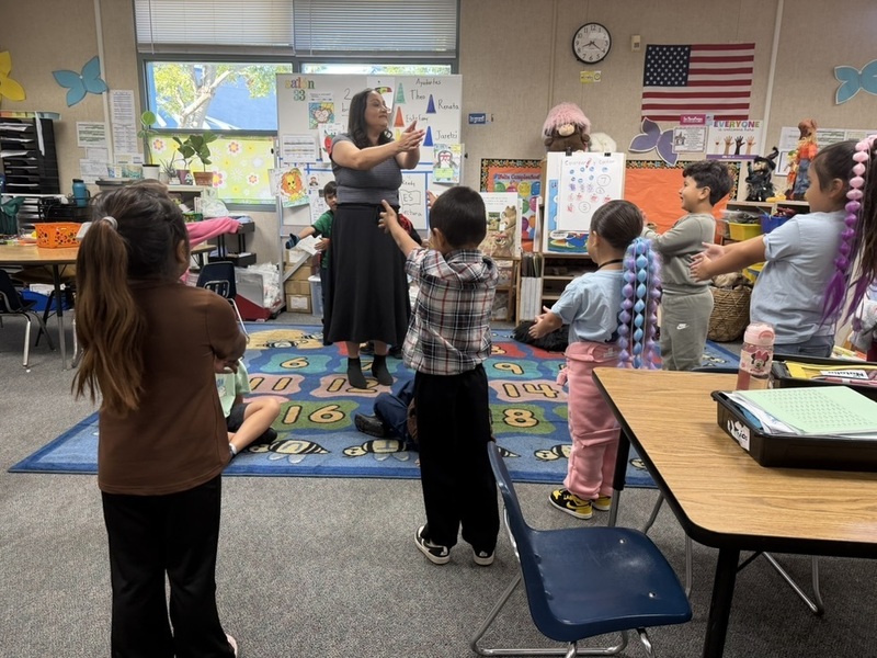 A teacher starts the day by dancing and singing with her students.
