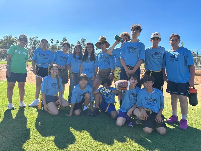 Quantum Academy Flag Football Team students pose with their coaches.  Los estudiantes del equipo de fútbol bandera de Quantum Academy posan con sus entrenadores.