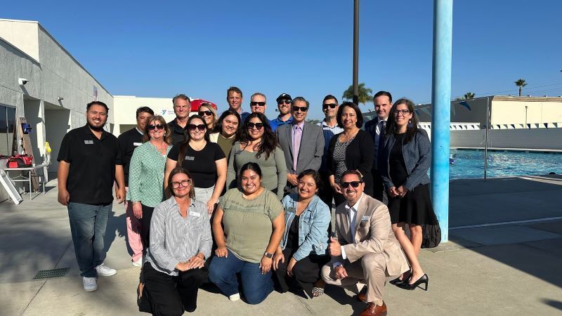 YMCA and EUSD staff pose in front of a swimming pool.  El personal de YMCA y EUSD posa frente a una piscina.