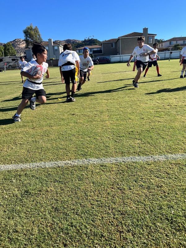 Students play flag rugby.  Las estudiantes juegan bandera de rugby.