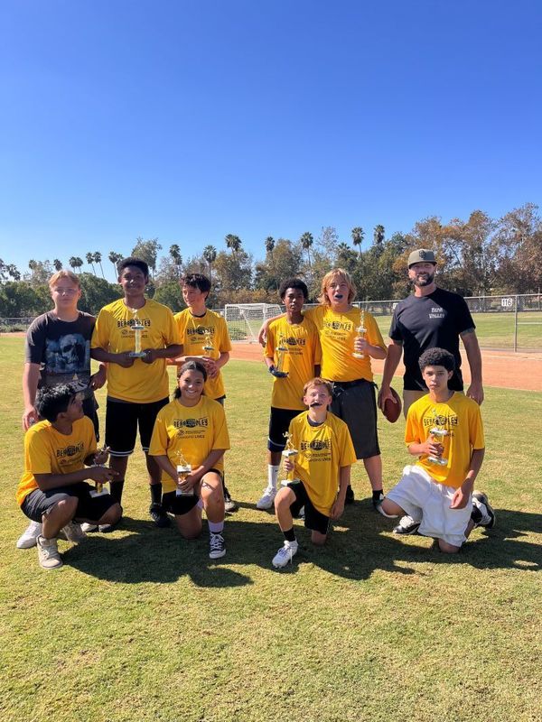 8 football players and 2 coaches holding trophies