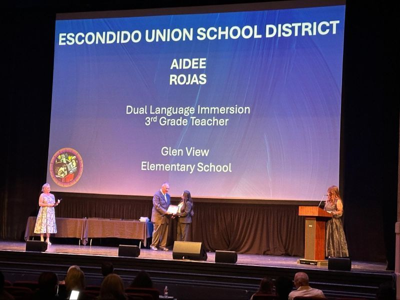 Aidee Rojas accepts her award on stage  at the San Diego County Biliteracy Symposium.