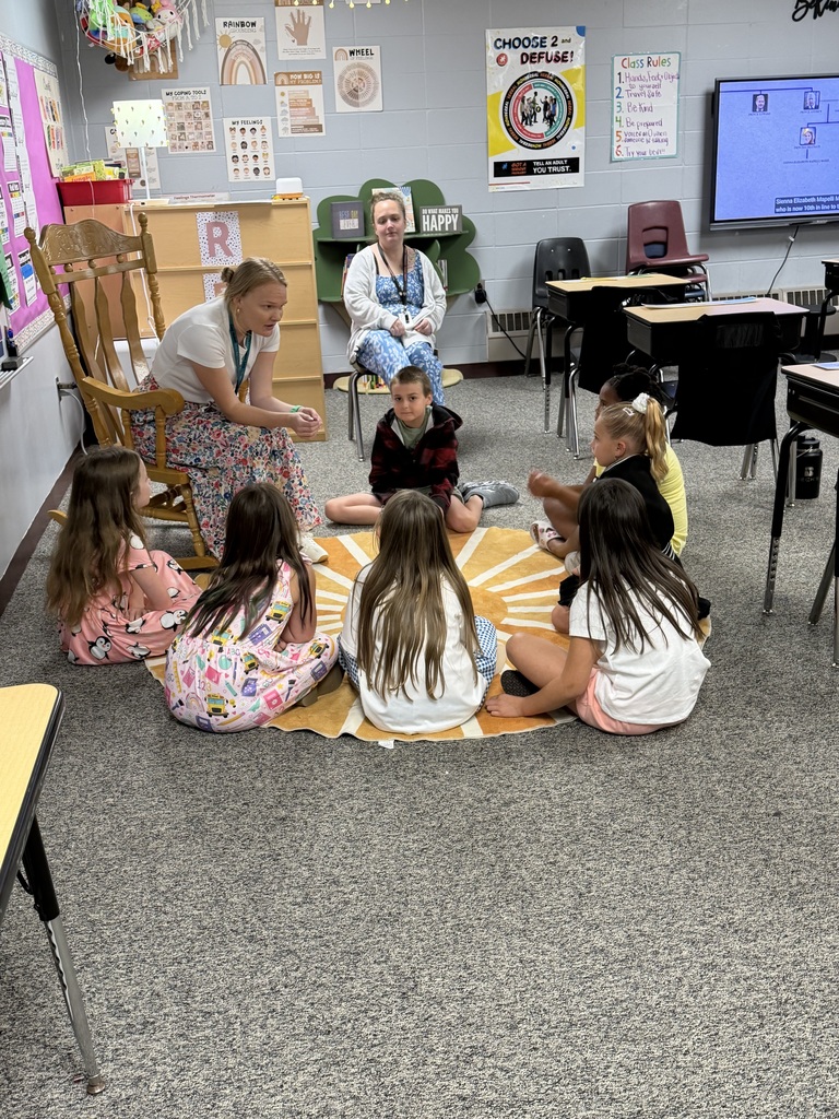 Students sitting in a circle on the floor listening to teacher