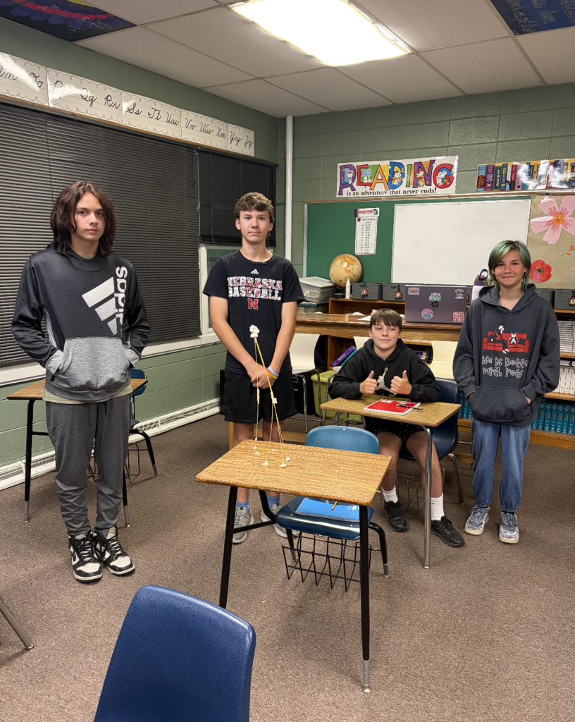 Four students smiling with their project