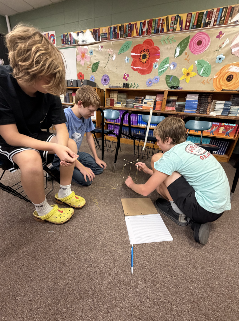 Three students sitting on the floor to work on project