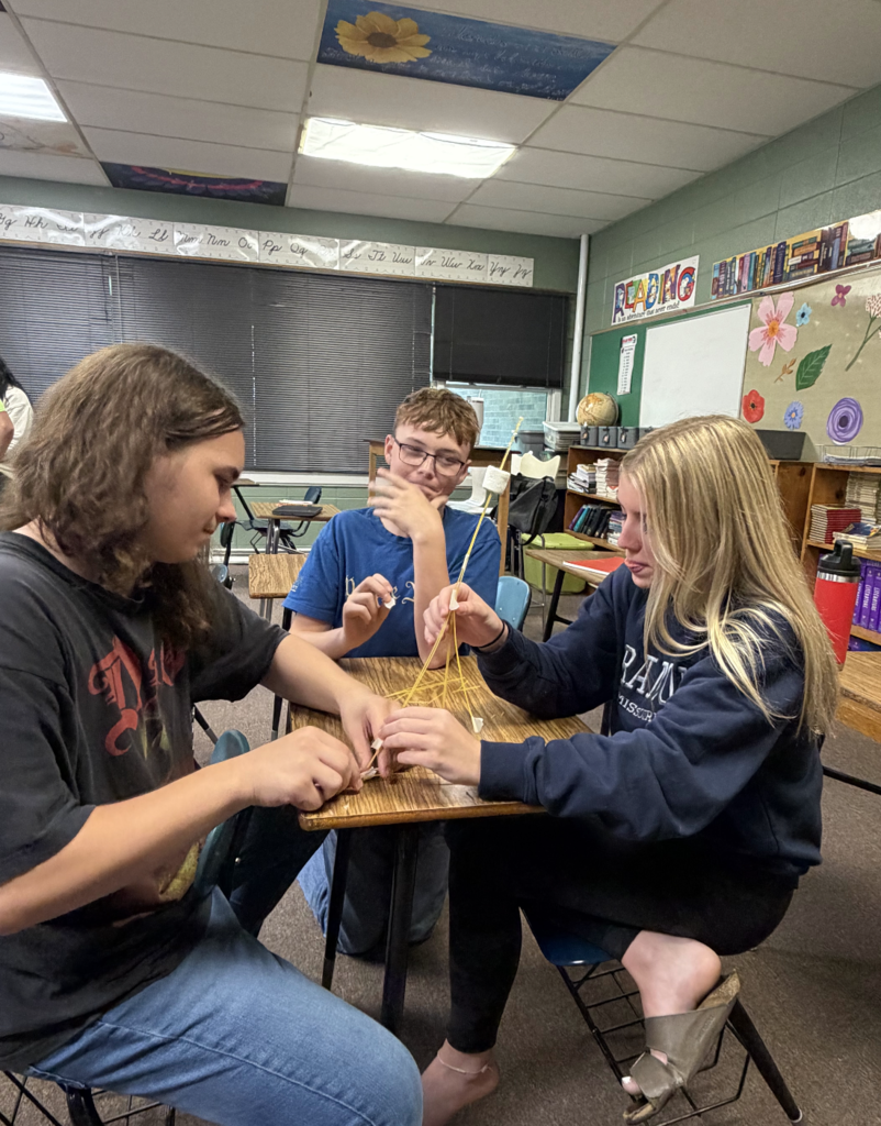 Three students working on project in a classroom