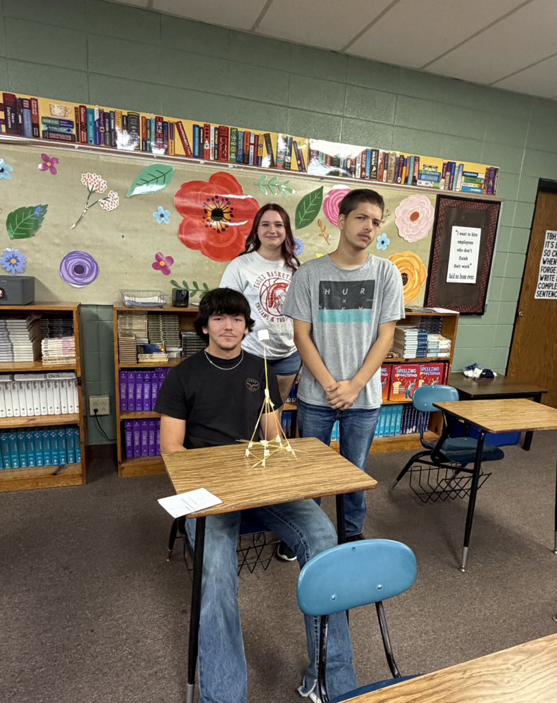 Three students smiling with their project