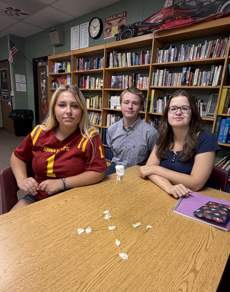 Three students posing for photo with their project