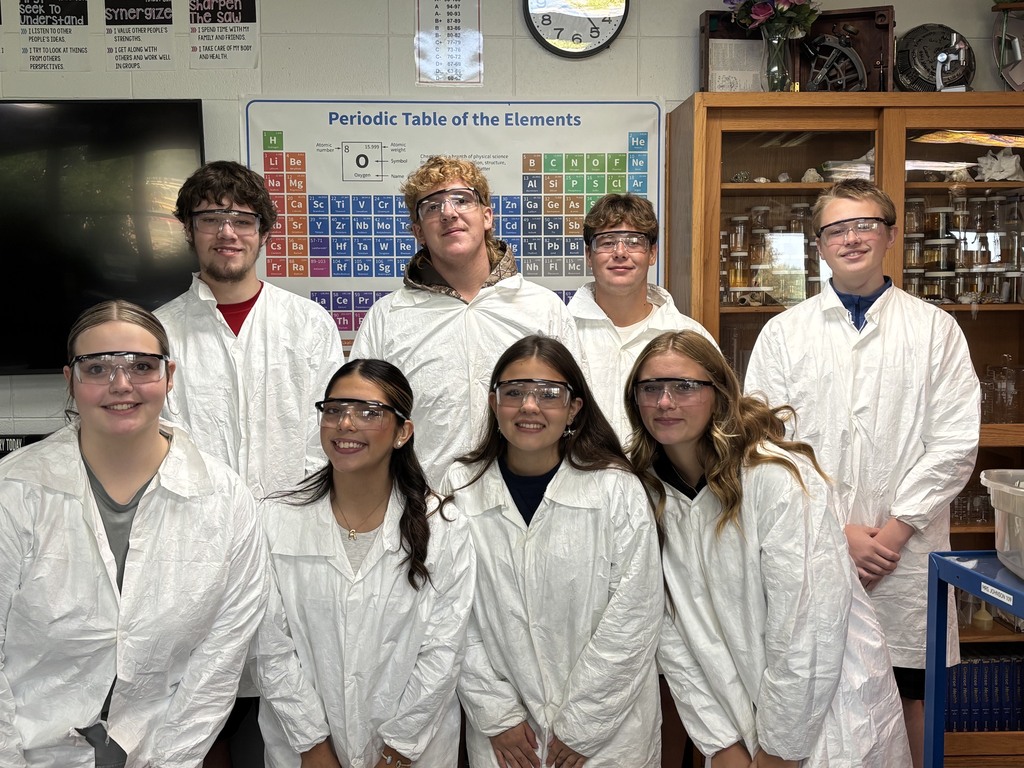 Group of students wearing lab coats in a science classroom