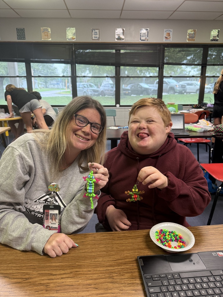 Student and teacher smiling with beaded artwork