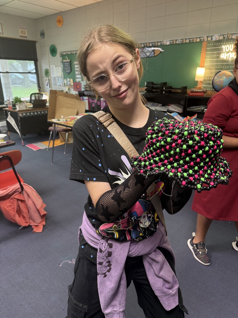 Student showing a beaded hat that she created