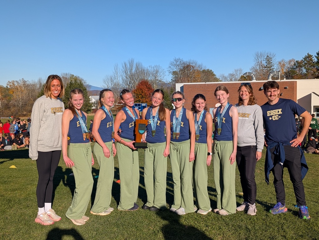 Group of students in matching blue and green outfits on a field with medals. A building is in the background.
