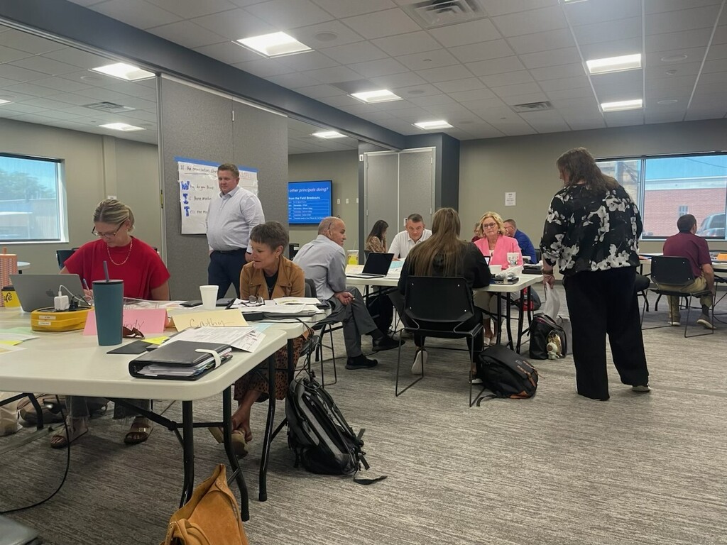 professional men and women, some sitting, some standing in a conference room