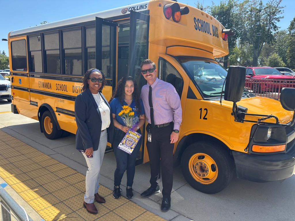 No text Image of three adults smiling in front of a school bus