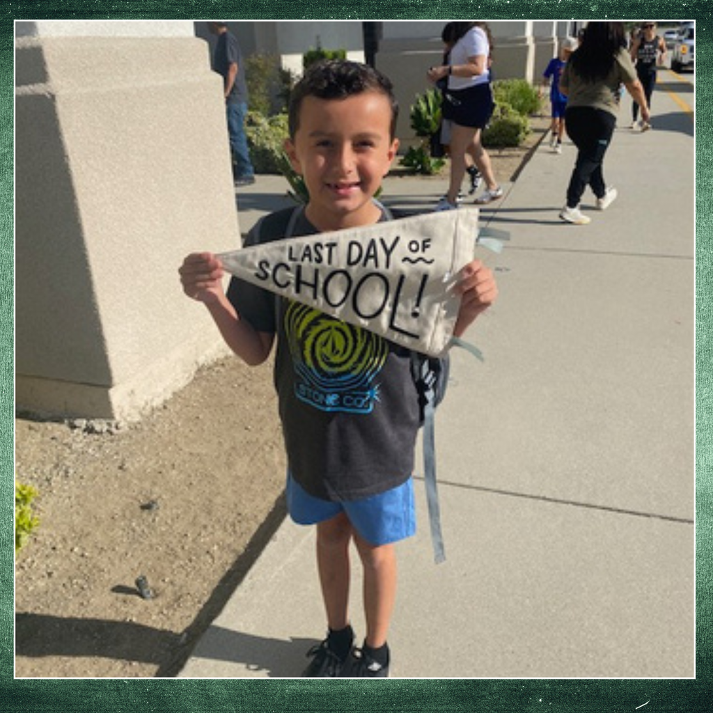 No text: Image of a boy holding a banner that says last day of school