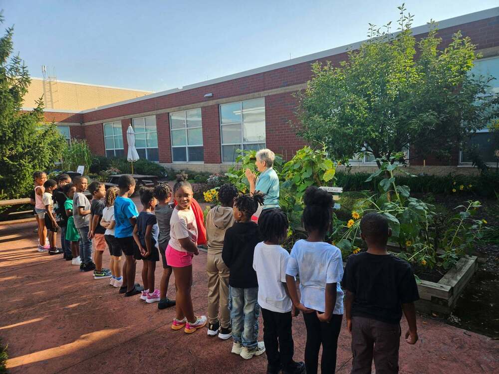 Ms. Galandiuk in the Bluestone Garden with students lined up while she presents.