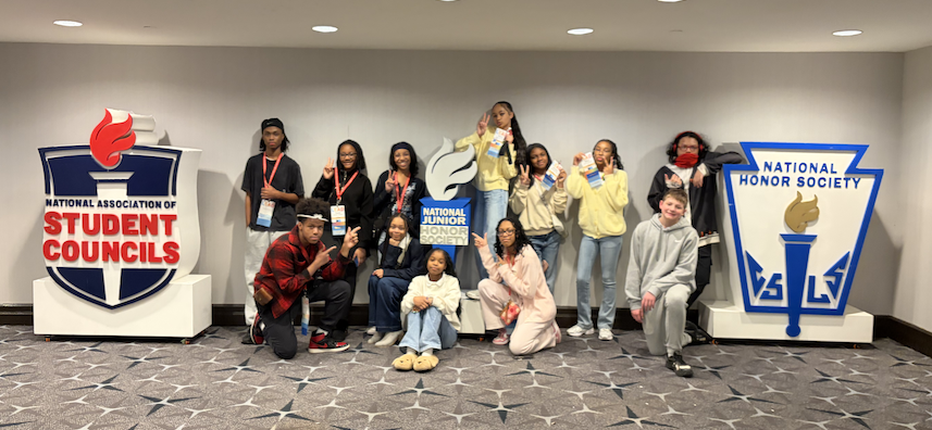 NJHS Students posing for a photo with large National Honor Society and National Association of Student Councils Statues