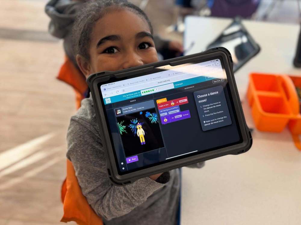 Child Holding iPad displaying work.