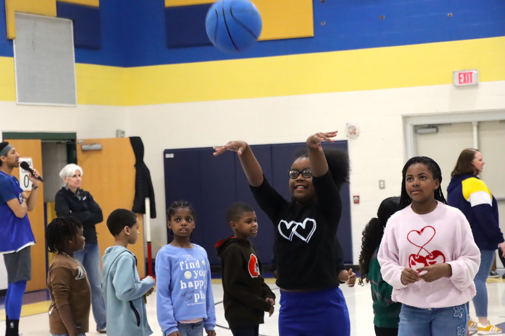 An Arbor student shooting a blue basketball during their Best Behavior Bonus. Students in the background watch the shot.