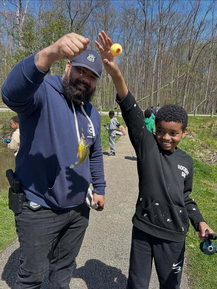 EPD Officer Ricky Jackson and a Shoreview Elementary student holding a fishing line with a fish hooked on the end.