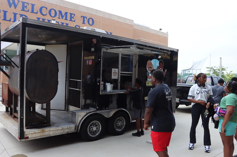 Attendees stand in line outside Carter's BBQ food truck to get a free snack during the event.
