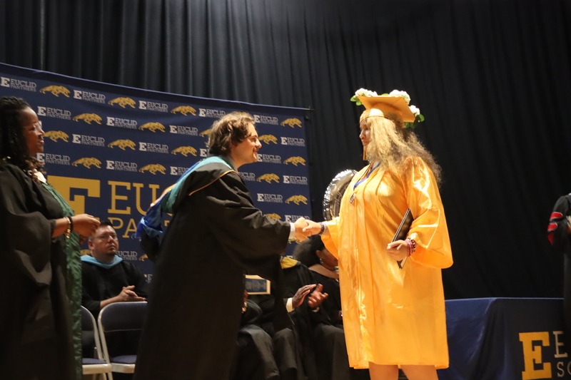 A graduate shaking hands with Board Member Evan Botzki