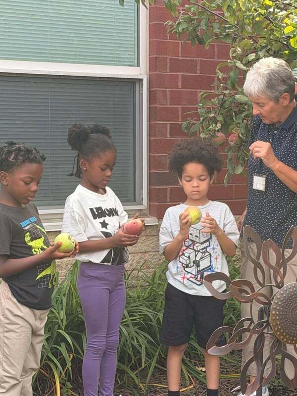 Ms. Galandiuk talks to three students who are holding apples and examining them.