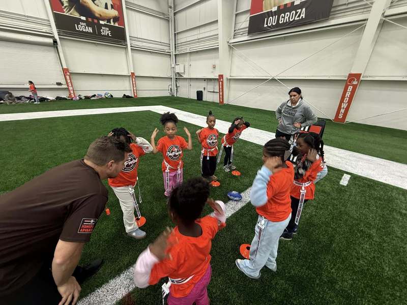 Girls participating in a football drill with adults from the Browns.