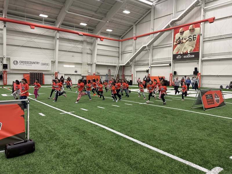 Girls participating in a football drill with adults from the Browns.