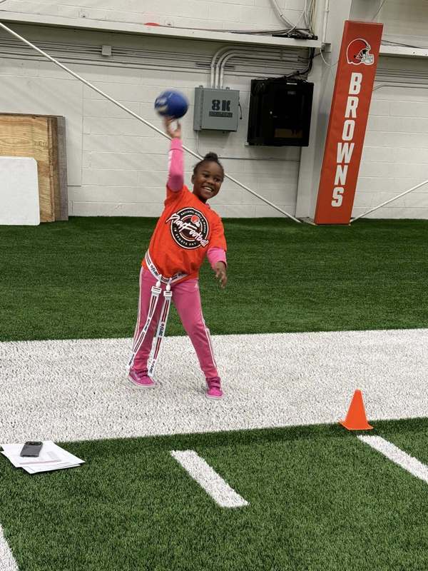 A girl throwing a blue football on the Browns Practice Field