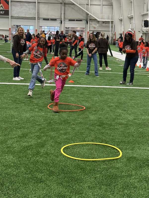 A girl running through hula hoops on the Browns practice field