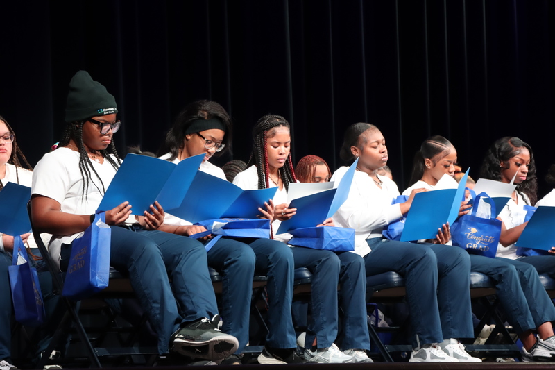 Graduates reviewing folders with information about their futures after graduating.