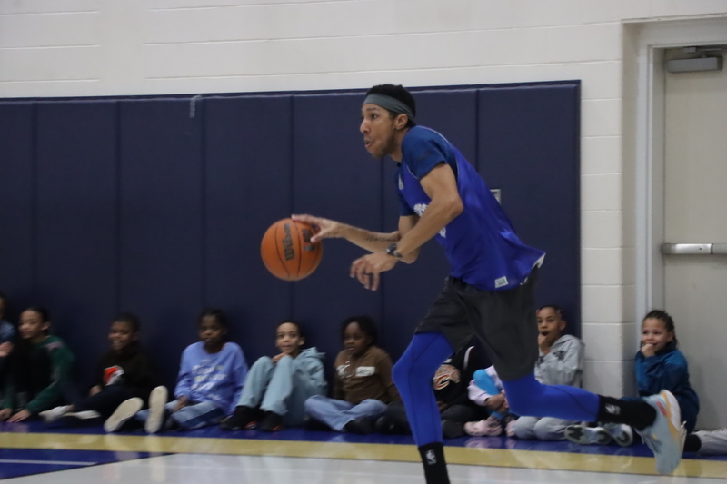 Mr. Johnson dribbling a basketball while playing against the high school athletes.