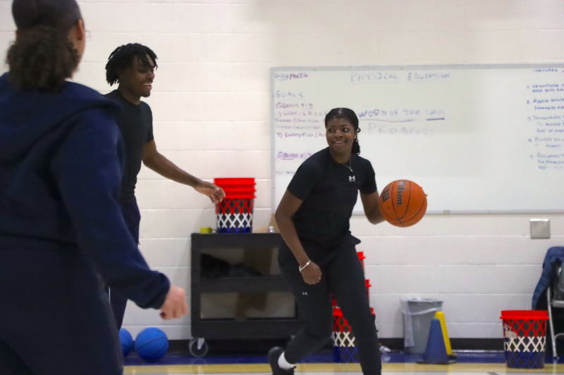 High school athletes playing basketball in a demonstration for the students.