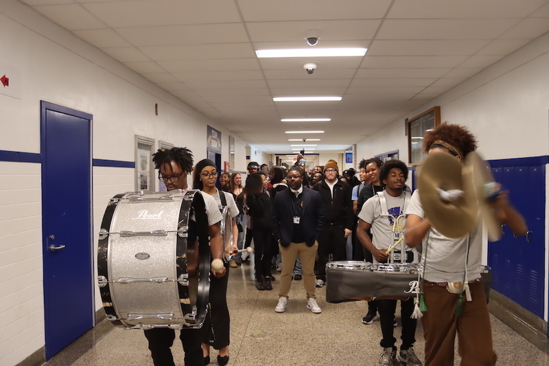 The Euclid Drumline leading a parade through the halls of Euclid High School with Mr. Russell and seniors following behind.