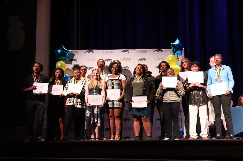 Scholarship winners pose with certificates and scholarship representatives during an academic awards and recognition ceremony.