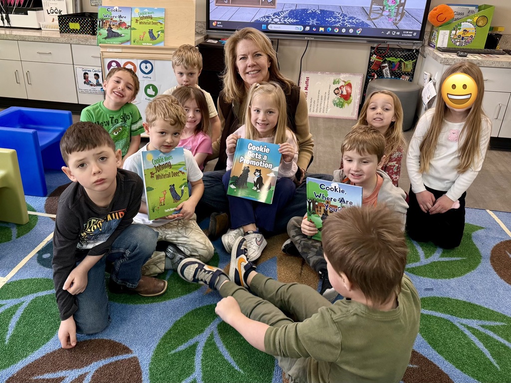 PreK student pose with author Yvette Mannon and her books.