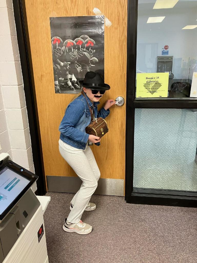 4th grade spy in black hat and sunglasses sneaking out the door with her treasure chest prize.