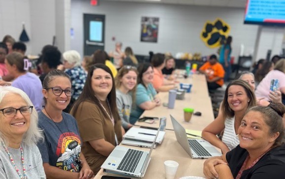 Group of teachers sitting at table with breakfasts and beginning welcome back meetings