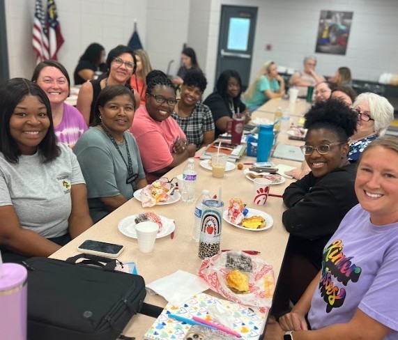 Group of teachers sitting at table with breakfasts and beginning welcome back meetings