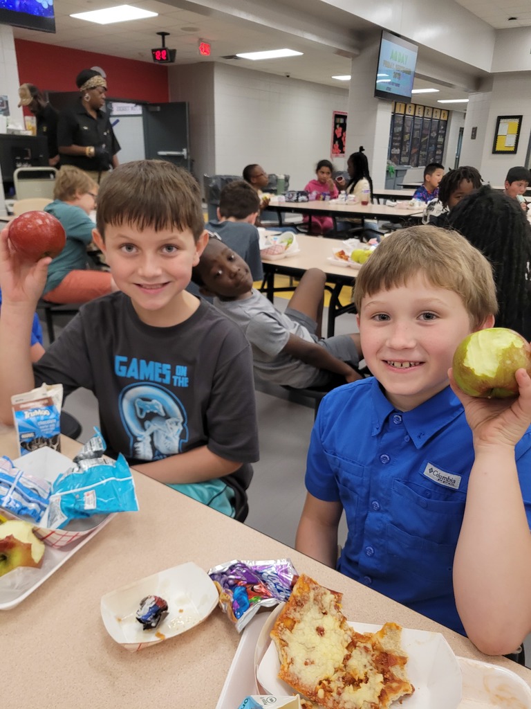Elementary students holding apples at lunch.