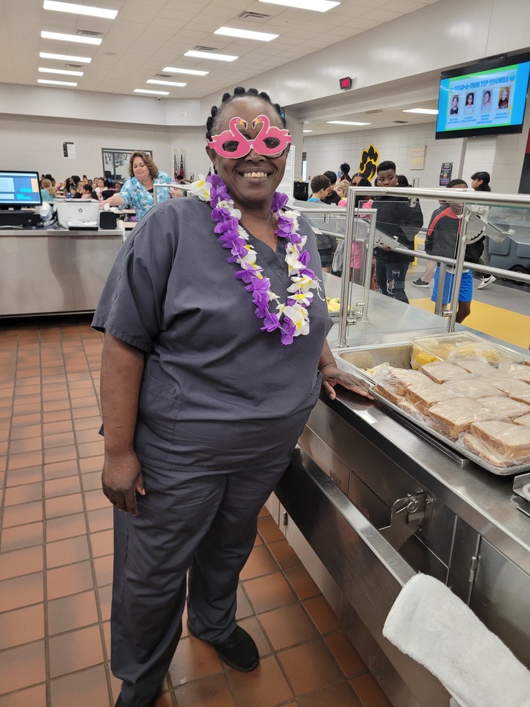 A school nutrition staff member posing with leis and fun glasses.