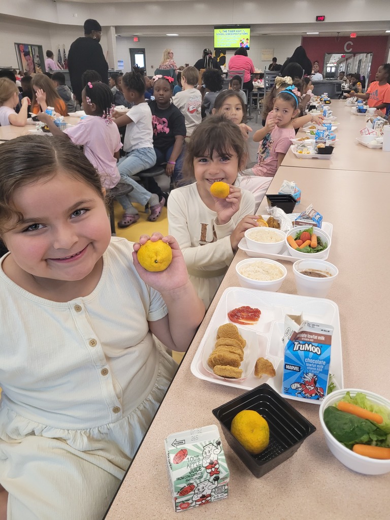 Elementary students holding a Kishu mandarin.
