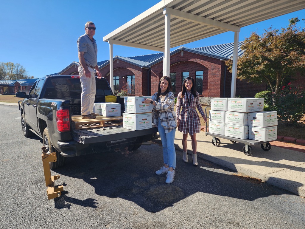 Larry Blocker delivering sweet potatoes donated by Bland Farms to Claxton Elementary School. Assistant principals, Blair Saylor and Sarah Rountree, assisted in unloading the sweet potatoes.