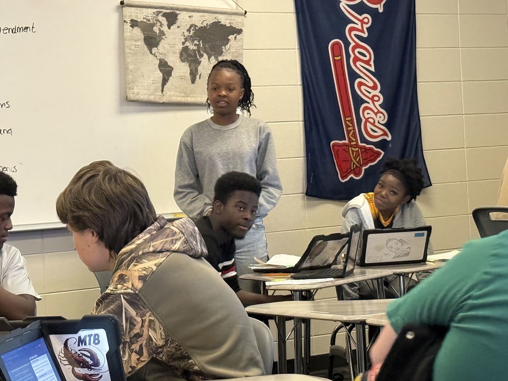 Image showing ⚖️ Order in the Court: Coach Lanier’s Class Takes on the Supreme Court! 🏛️ What happens when a peaceful protest turns chaotic, and a student is suspended without a chance to tell her side of the story? That was the high-stakes scenario facing Coach Lanier’s students recently! After studying Civil Rights, Civil Liberties, and Due Process, our Tigers put their knowledge to the test using an interactive iCivics court simulation. The case centered on a student’s right to a fair process and whether her school overstepped when they suspended her for carrying a protest sign. The Courtroom Roles: The Defense: Arguing for the school’s right to maintain order. The Plaintiff: Fighting for the student's right to due process and free speech. The Supreme Court Justices: Reviewing the arguments and making the final ruling. This simulation was a powerful way to bridge the gap between our current unit and the Judicial Branch, showing exactly how the Supreme Court functions as an appellate court. Our students did an incredible job researching their positions and preparing for "heated" counter-arguments! 🐯🖤💛 #CivicsInAction #iCivics #DueProcess #SupremeCourt #FutureLawyers #TigerPride